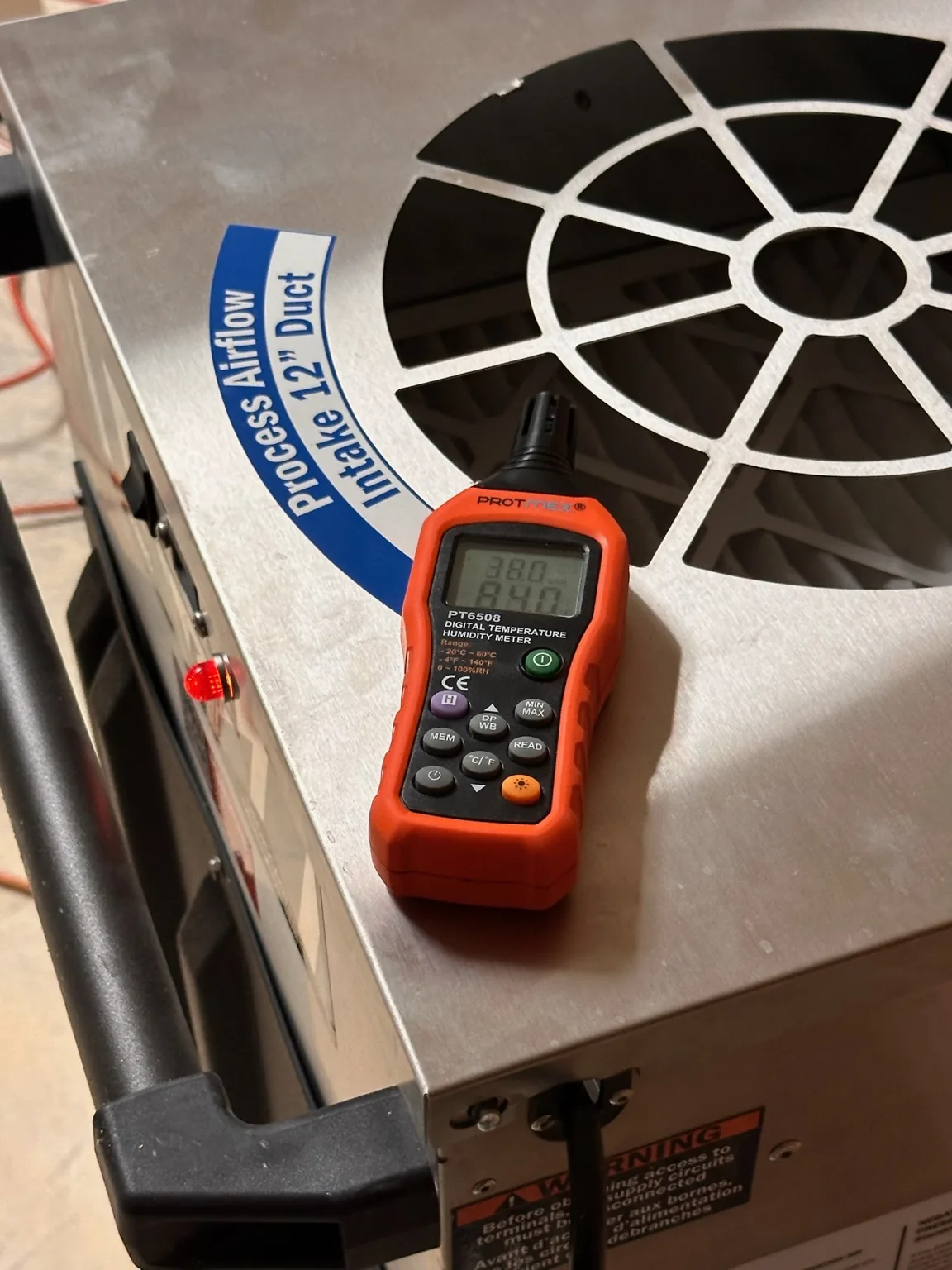 Process-airflow equipment documented with an environmental meter.