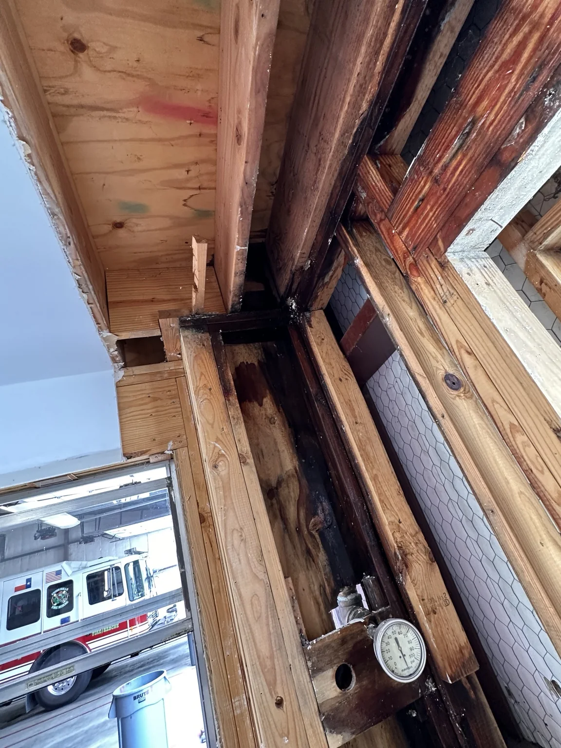 Opened wall assembly in a municipal fire station with fire apparatus visible in the adjacent bay