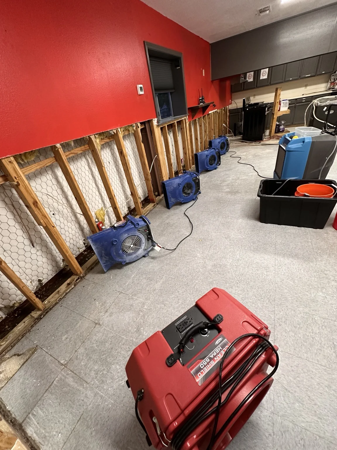 Multiple air movers and dehumidification equipment positioned along an exposed wall assembly