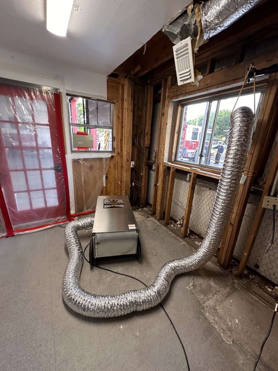 Emergency structural drying equipment operating inside a commercial property while first responders remain on scene outside